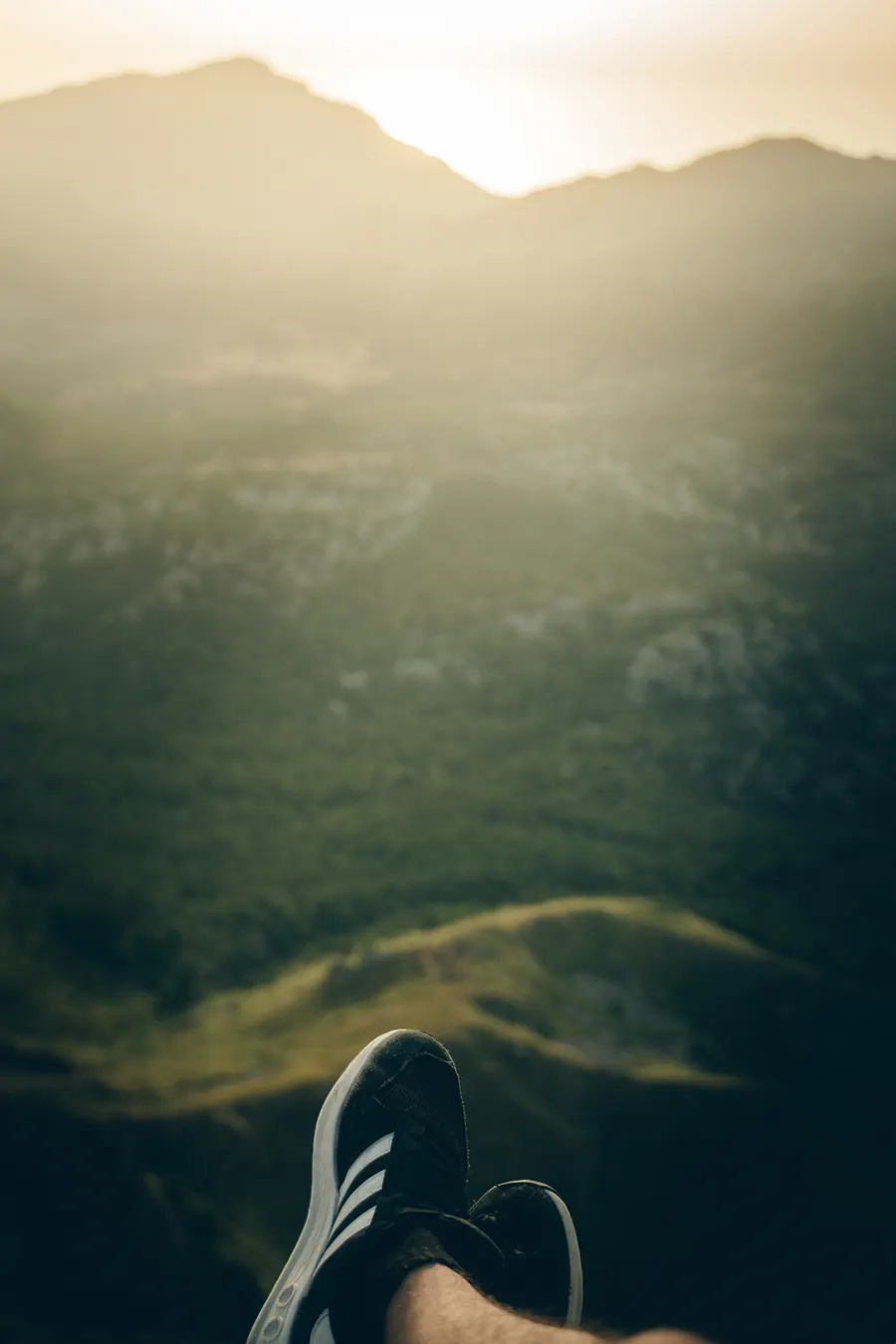 Blick vom Grat hinunter in ein grünes Tal, vorne ein Schuh.